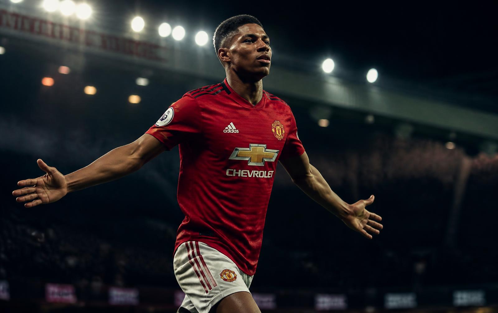 Footballer in a red shirt inside a floodlit stadium